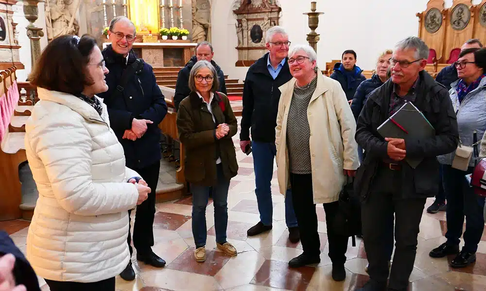 Mehrere Personen hören einer Kirchenführung zu.