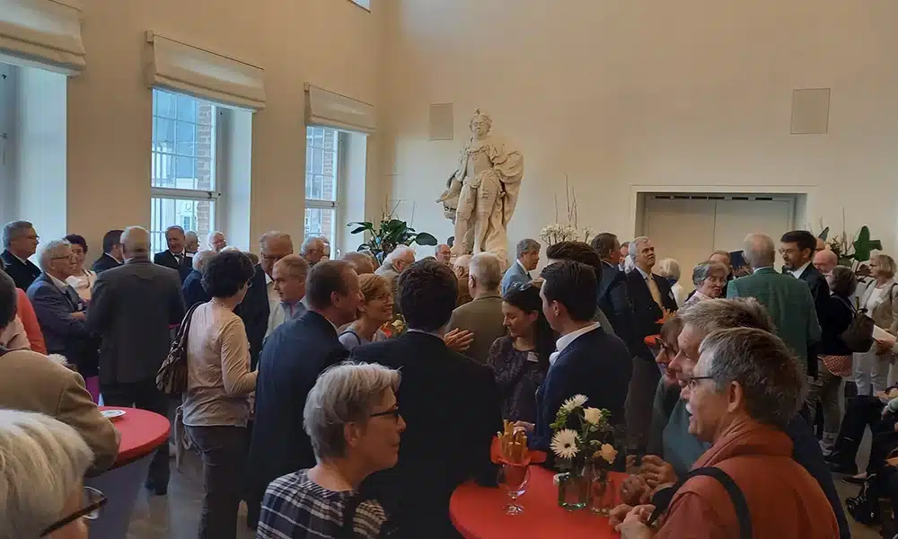 Viele Menschen stehen bei einem Empfang in einem Saal.