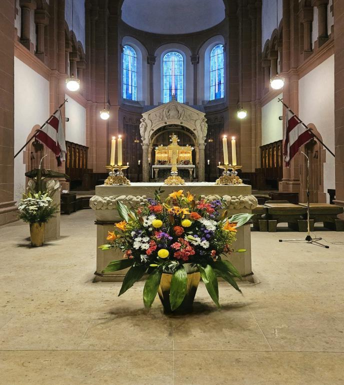 Blick in den Chorraum der Kirche St. Adalbero in Würzburg mit geschmücktem Altar und Blumengesteck